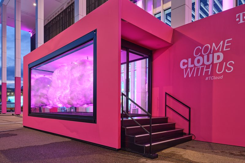 Magentafarbener Showcontainer in der Abenddämmerung, im Fenster eine angestrahlte Wolke, davor eine Treppe