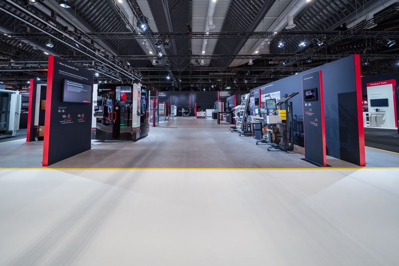 Hauptachse des Stands mit weißer Bodenbahn zwischen Maschinen und Wandscheiben
