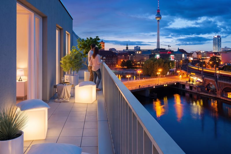 Visualisierung, 2026 mit KI veredelt und belebt: Balkon bei Nacht über einem Fluss mit Stadtlichtern, ein Paar am Geländer